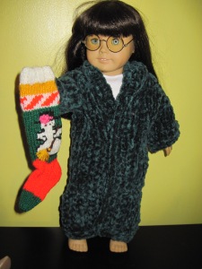 AG doll holding knitted Christmas stocking with a snowman holding a broom